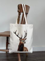 Stag tote bag with realistic stag artwork, eco-friendly linen shopping bag hanging on a wooden chair. Ideal tote bag for women and nature lovers.
