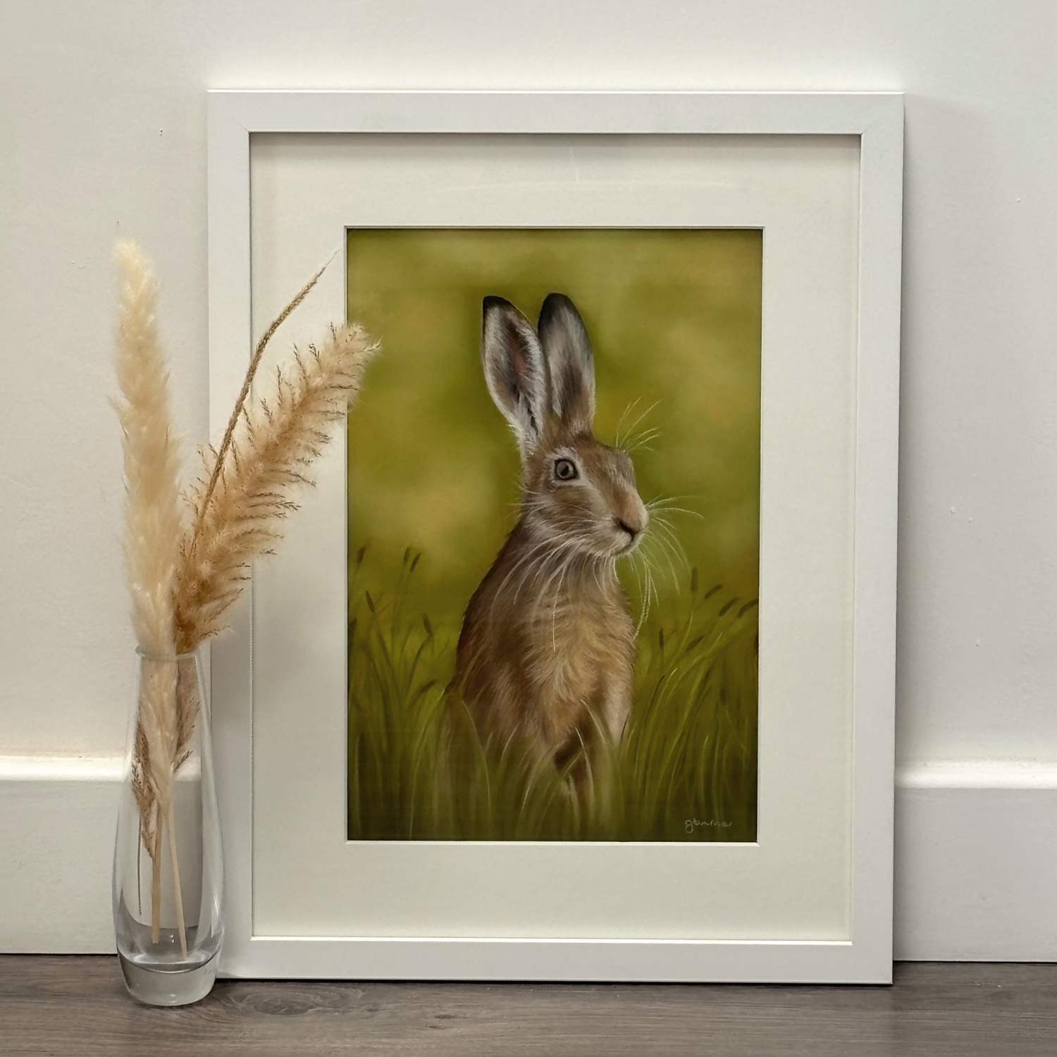 Framed 'Hare In The Grass' original artwork by Georgie Turner, ideal for country home decor. Displayed on floor with pampas grass for rustic charm.