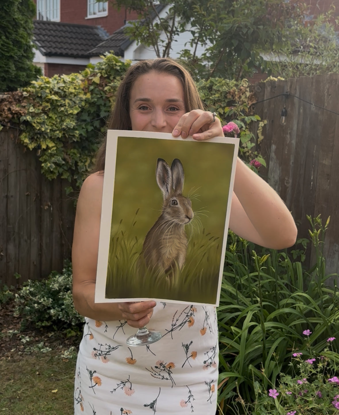 Woman holding 'Hare In The Grass' original painting by Georgie Turner outdoors. Perfect framed wall art for equestrian and country-style interiors.