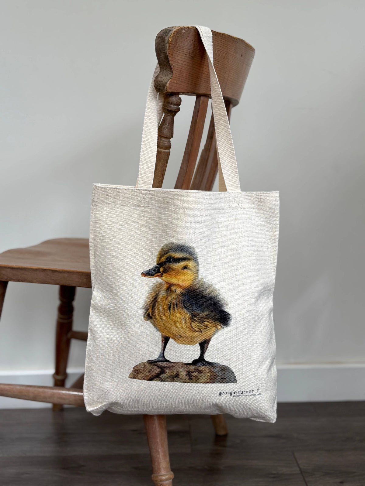 Eco-friendly duck tote bag hanging on a wooden chair, showcasing detailed duckling print. Stylish and sustainable tote bag for women.