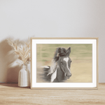 Galloping Foal Fine Art Print displayed in a light wood frame on a wooden shelf with a neutral vase, ideal for equestrian-themed home decor.