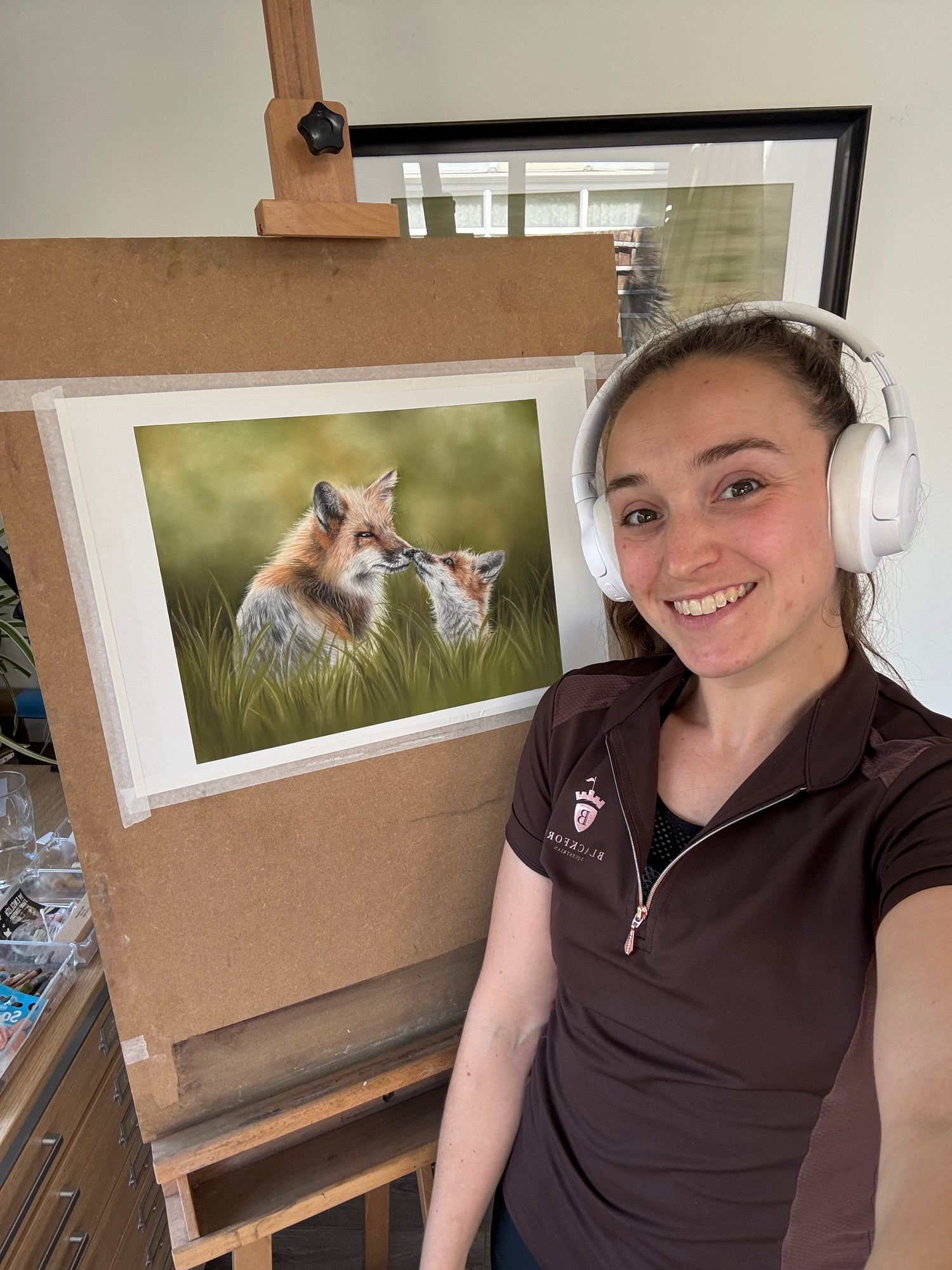 Artist posing with her Fox & Cub original painting on an easel, showcasing British wildlife art perfect for country-themed interiors.
