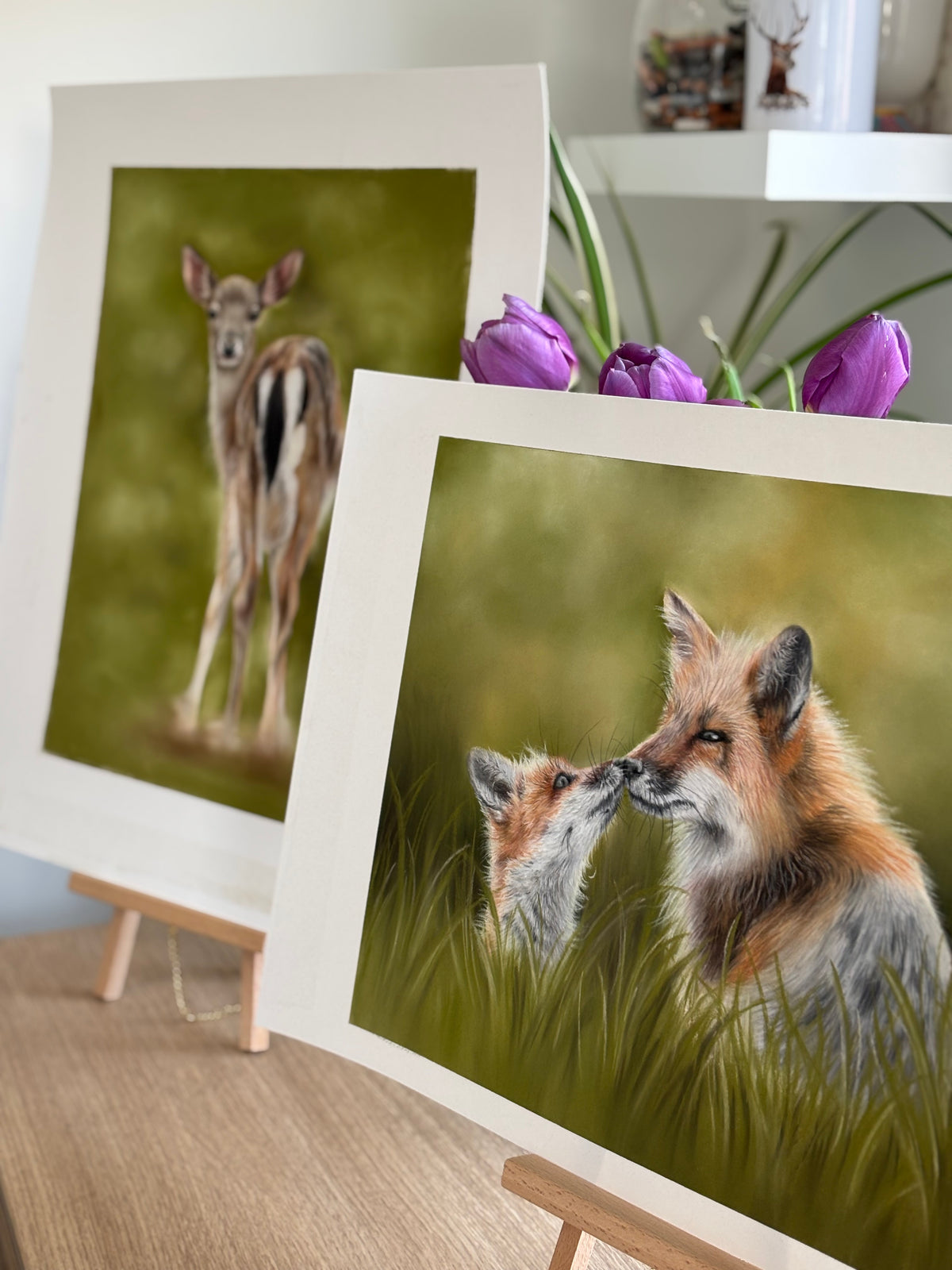 Fox & Cub and deer wildlife paintings on easels with tulips in background, ideal for rustic and equestrian-inspired home wall art collections.