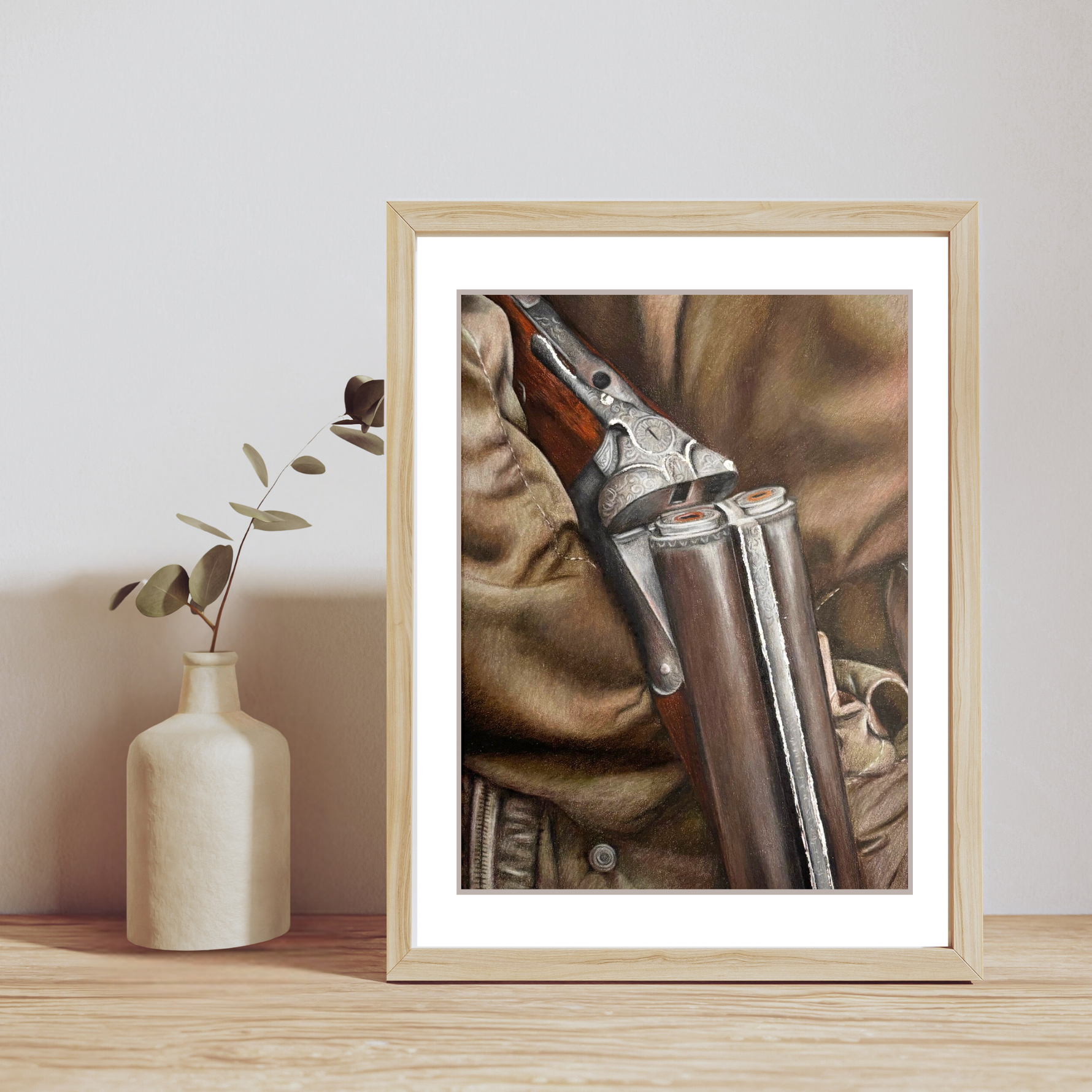 Country Shoot Art Print in light wood frame on wooden shelf with ceramic vase, showcasing fine detail of shotgun and countryside attire.