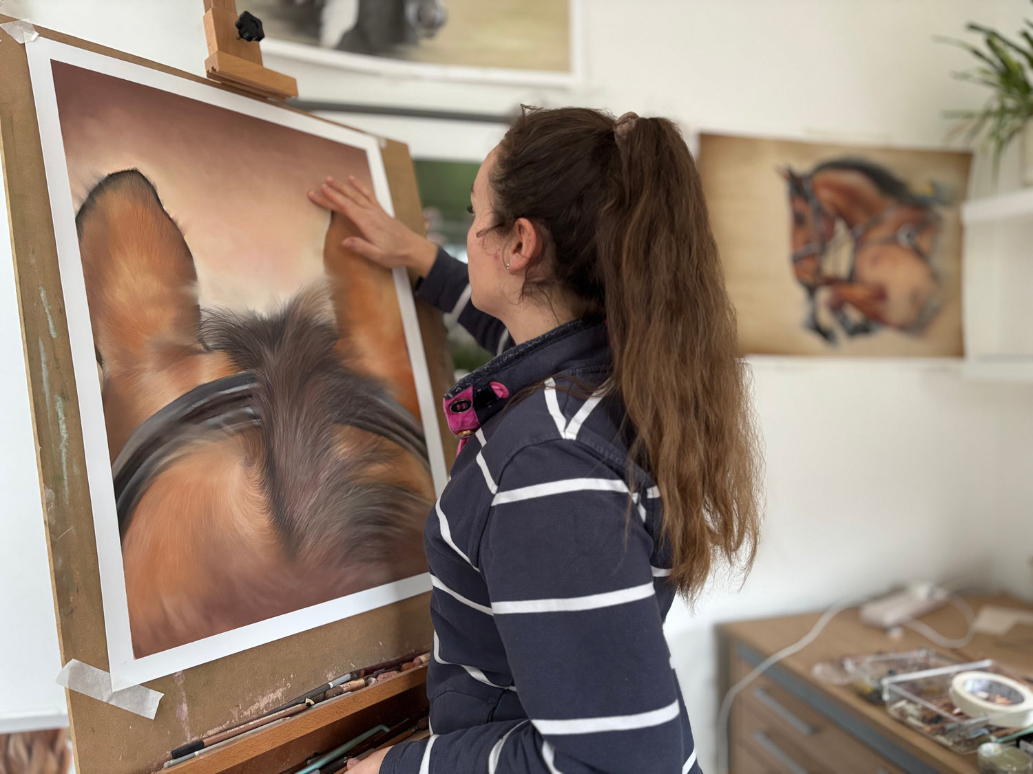 Artist working on a painting of a horse in an art studio.