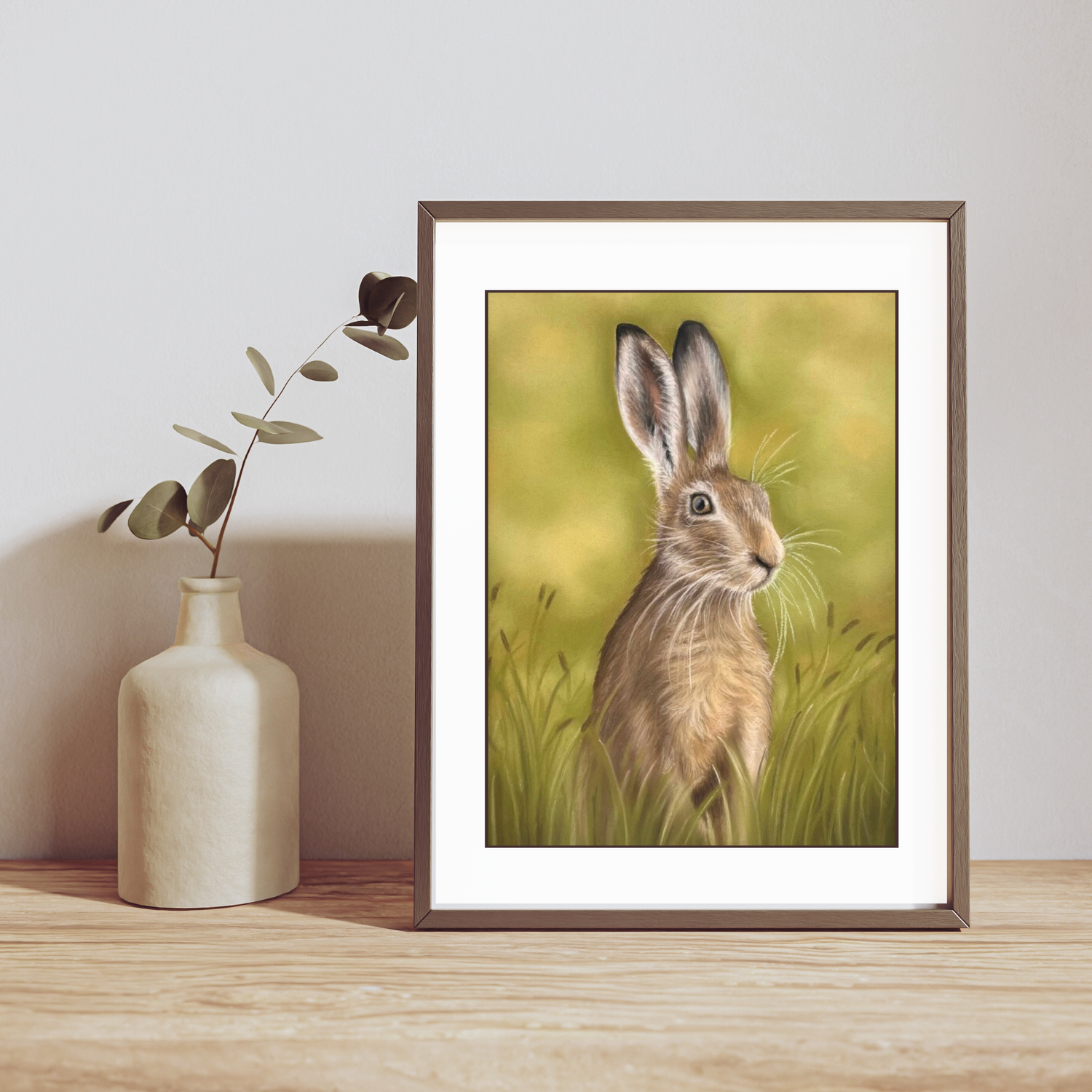 Hare In The Grass Fine Art Print On Paper displayed in a wooden frame on a shelf, ideal for British countryside home decor.