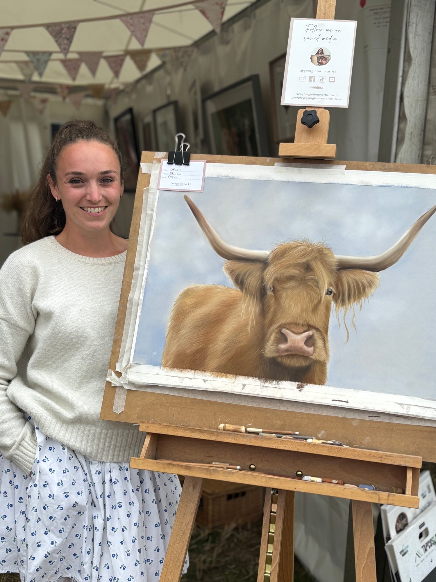 Artist beside Scottish Highland Cow Wall Art | Original Pastel Painting on easel, showcasing detailed farm animal artwork in progress.