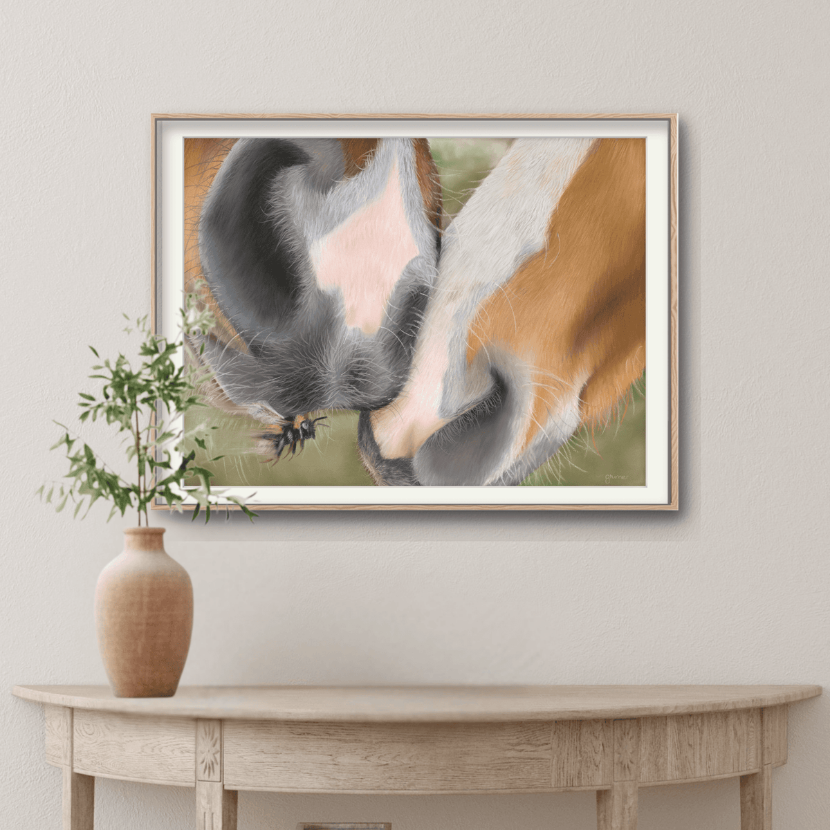 Framed Horse Muzzle Fine Art Print hanging above a console table, showcasing a soft equestrian moment between two horses in countryside tones.