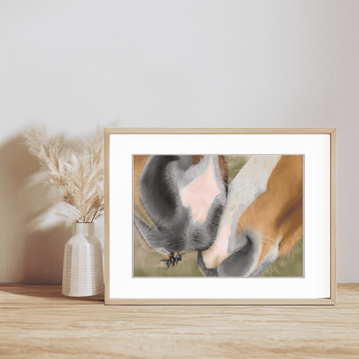 Horse Muzzle Fine Art Print displayed in a light wood frame on a wooden surface, featuring a close-up of two horse muzzles touching gently.