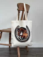Showjumping horse and a horseshoe on a linen tote bag hung over a chair