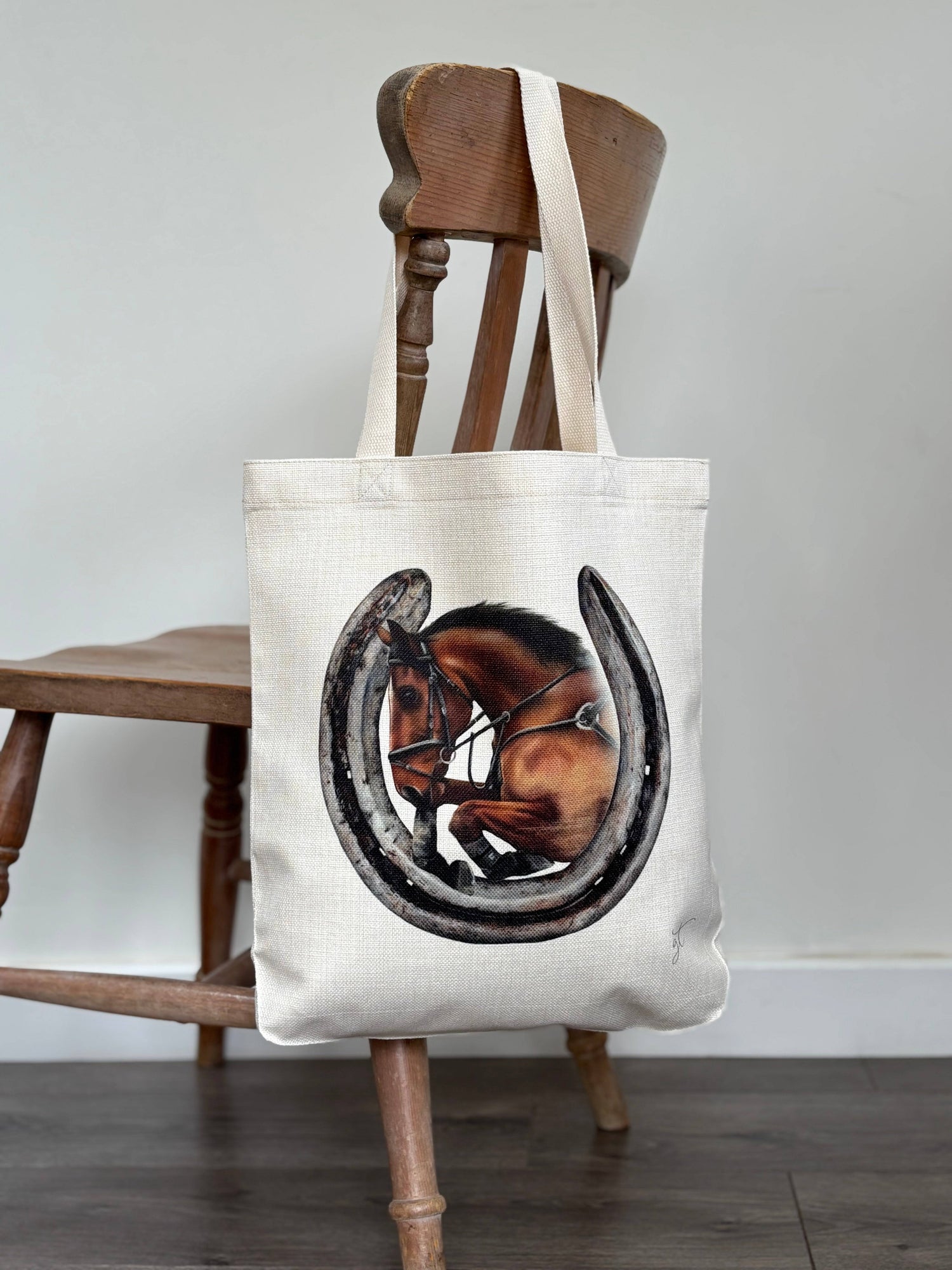 Showjumping horse and a horseshoe on a linen tote bag hung over a chair