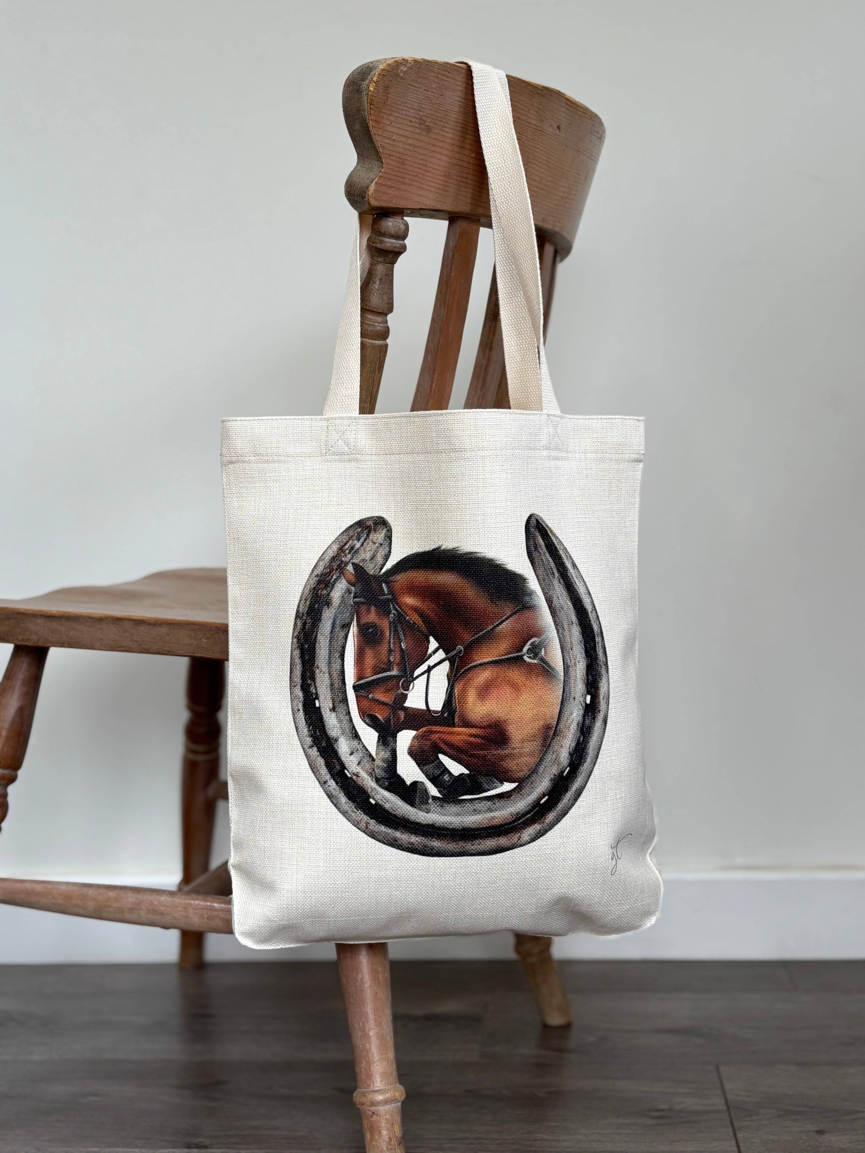 Showjumping horse and a horseshoe on a linen tote bag hung over a chair