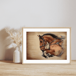 Showjumping Fine Art Print On Paper featuring a realistic horse mid-jump, framed and displayed on a wooden shelf with a neutral vase decor.