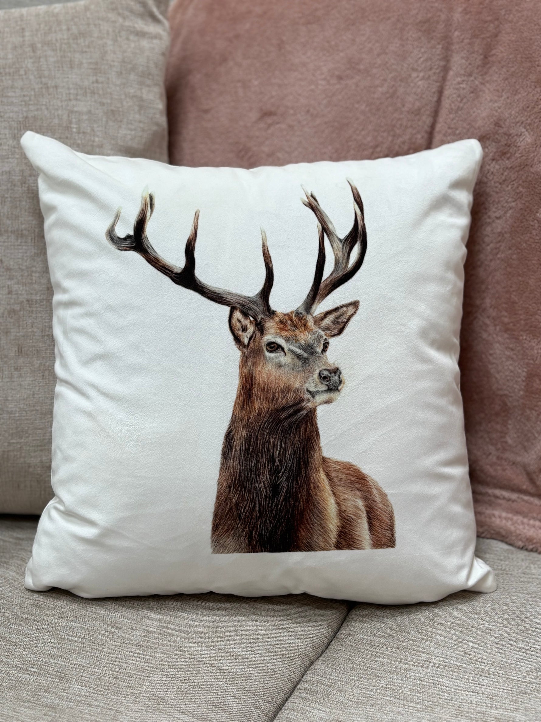 Stag cushion on a beige sofa with a pink throw in a country home.
