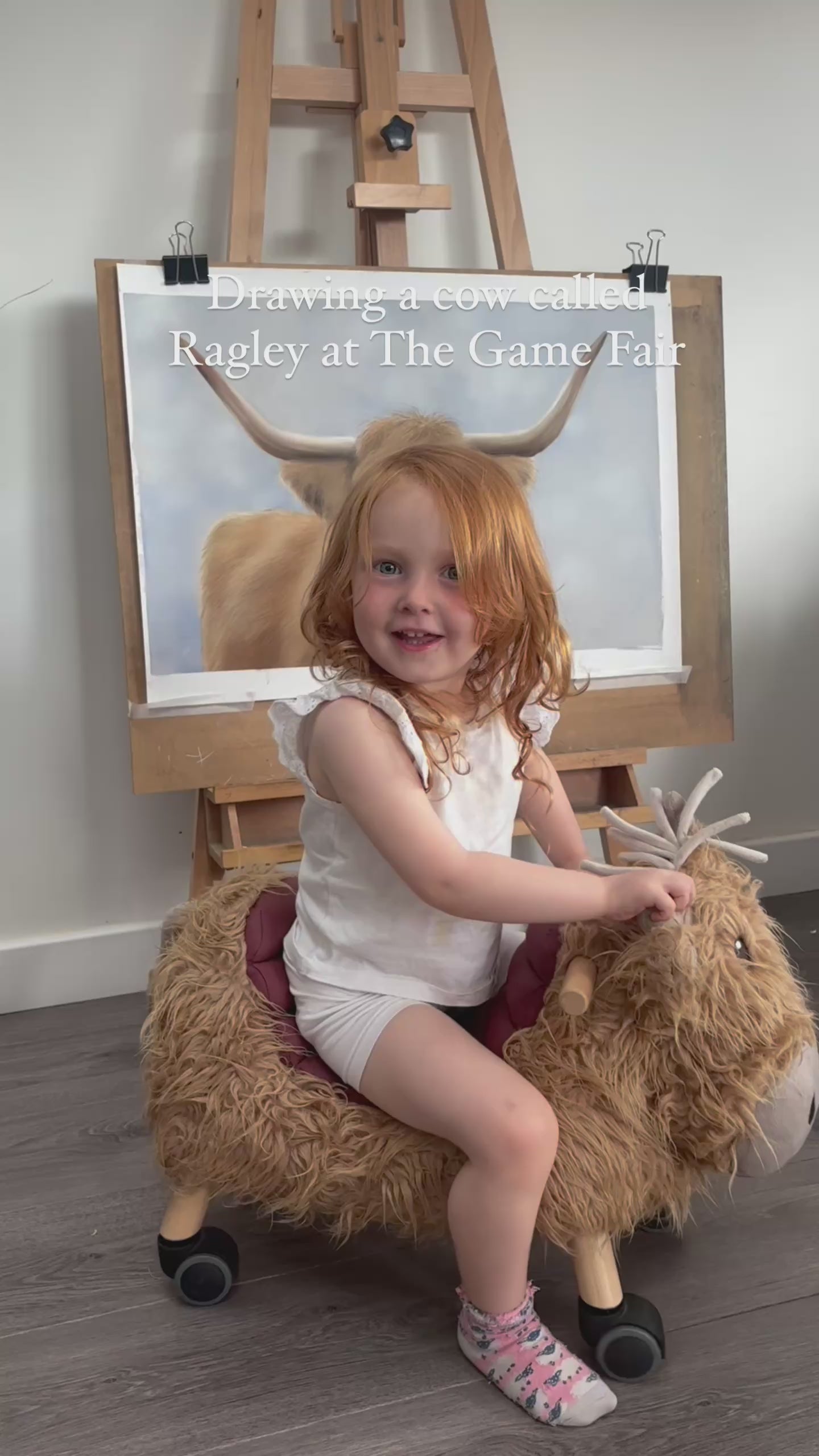 Child in front of Scottish Highland Cow Wall Art | Original Pastel Painting at art fair, emphasizing family-friendly farming artwork.