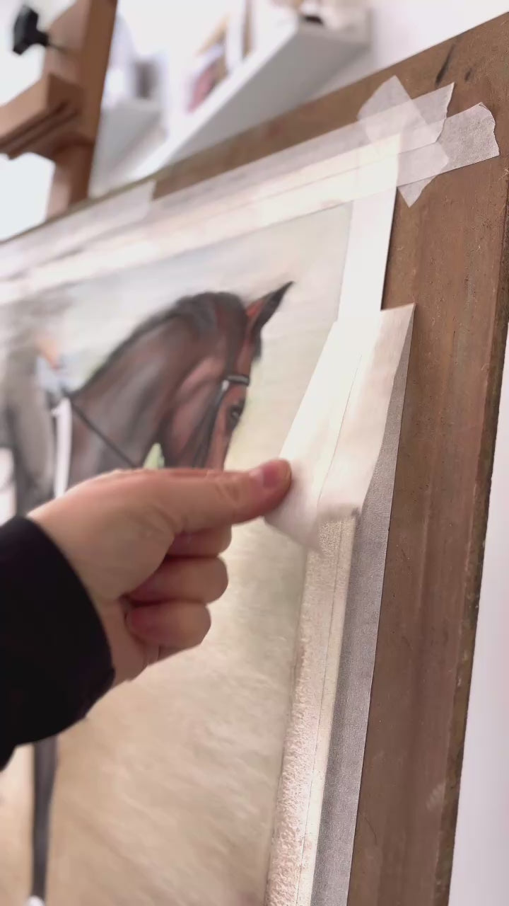 Close-up of artist peeling tape from dressage horse painting. Showcasing the final touches of original equestrian wall art for country home decor.