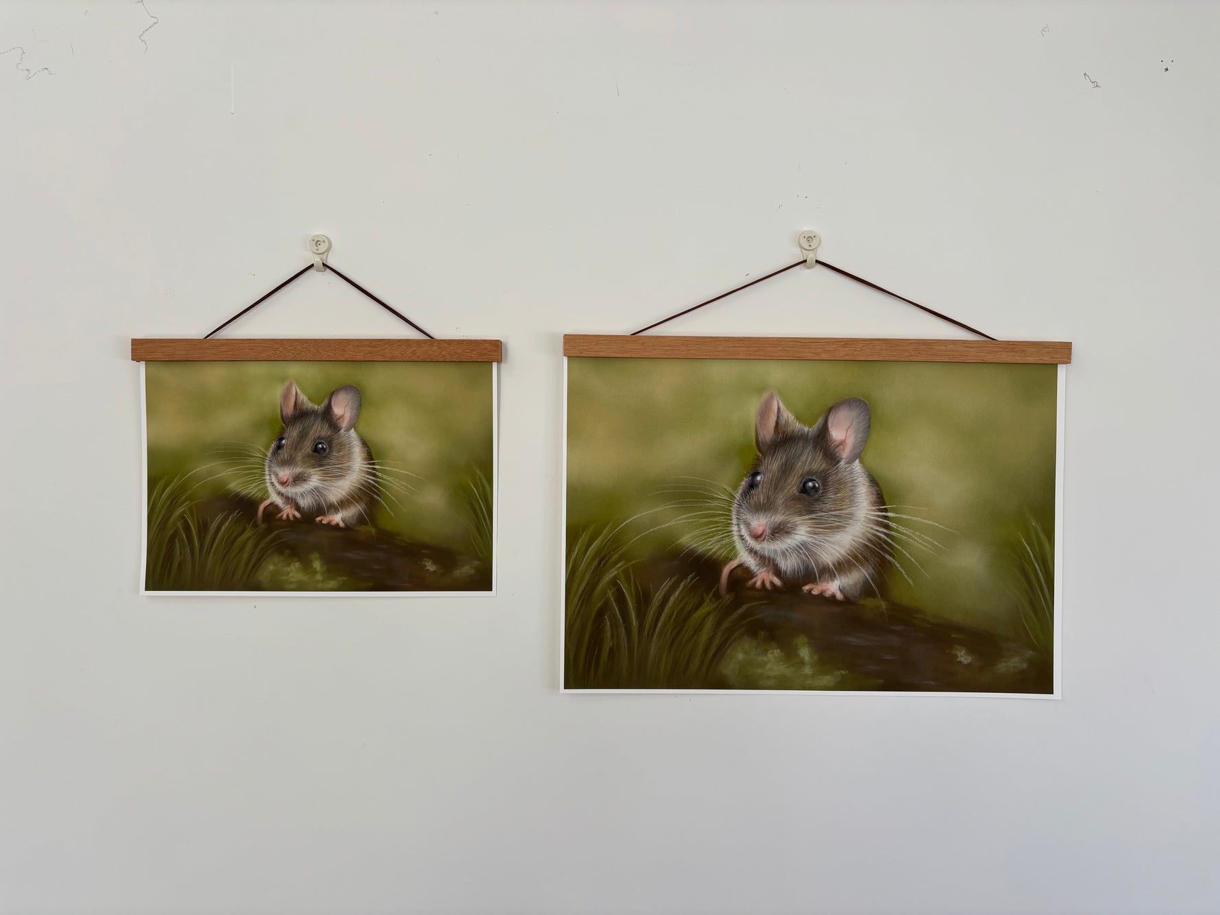 Two sizes of Field Mouse Fine Art Print On Paper hanging on a white wall with wooden hangers, perfect for British countryside-inspired interiors.