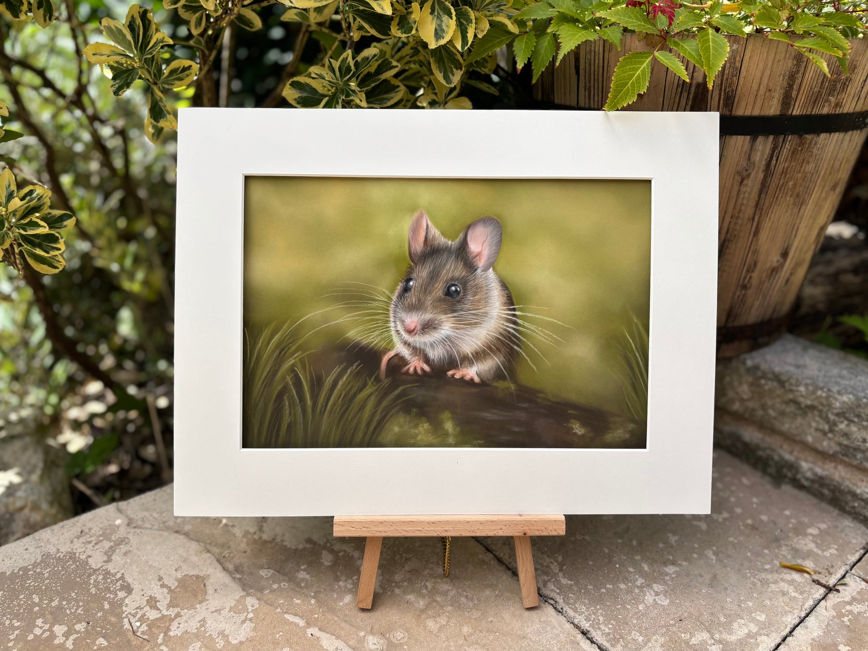 Mounted Field Mouse original artwork on easel with garden background, highlighting fine detail and natural tones for countryside-inspired decor.