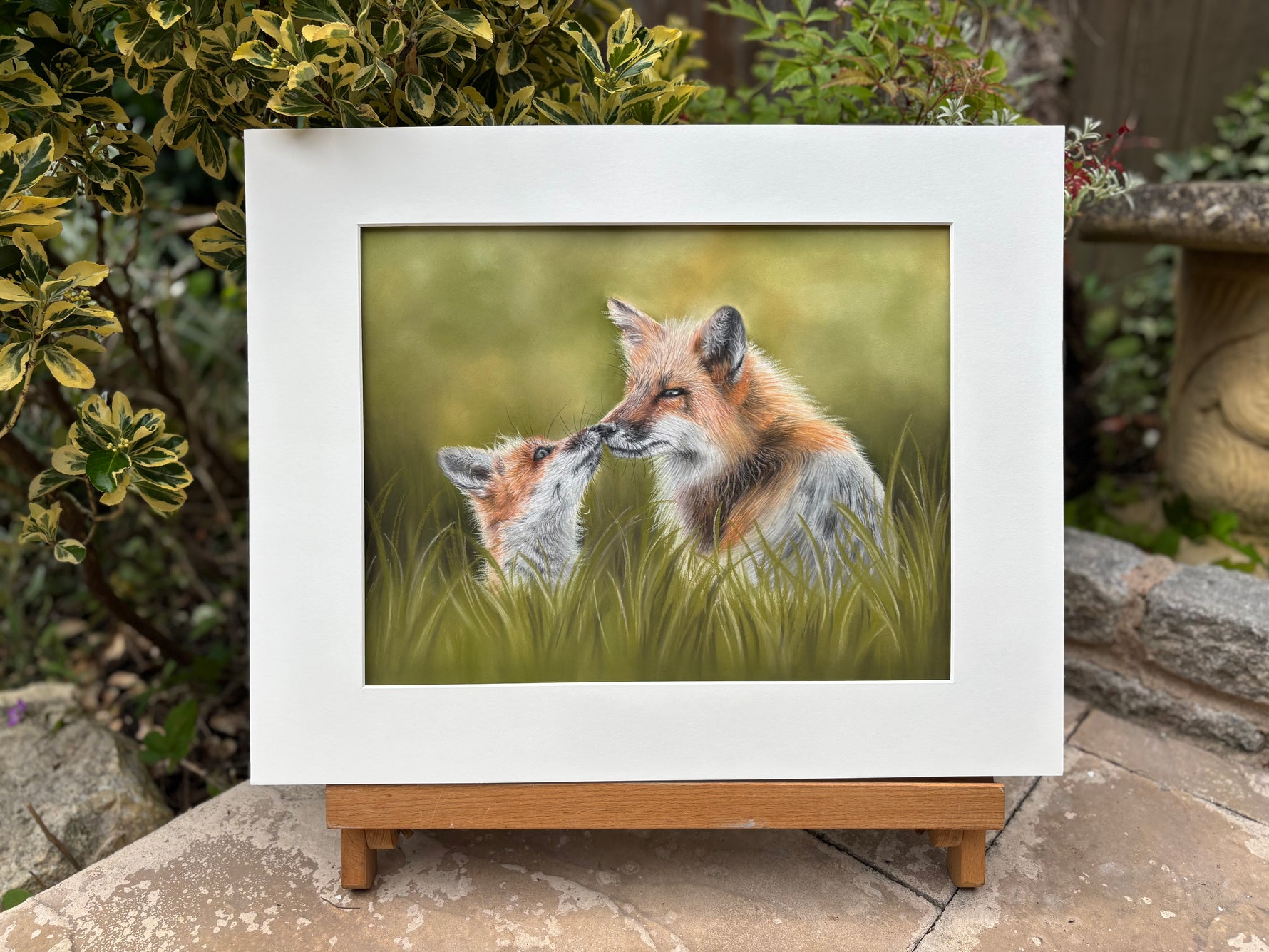 Framed Fox & Cub original artwork displayed outdoors on a wooden stand, perfect for garden-themed or country wildlife home decor.