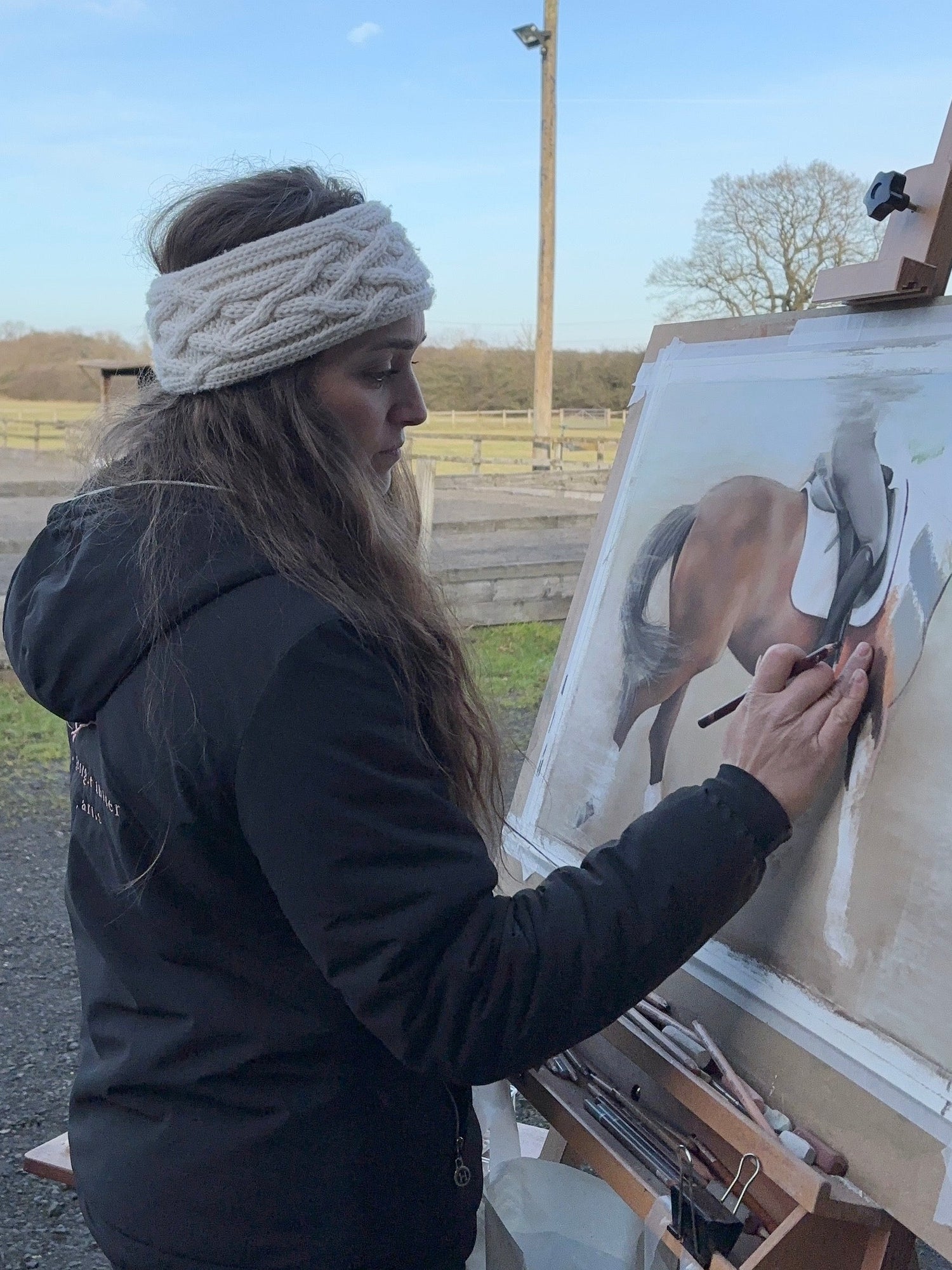 Person painting a horse on an easel outdoors
