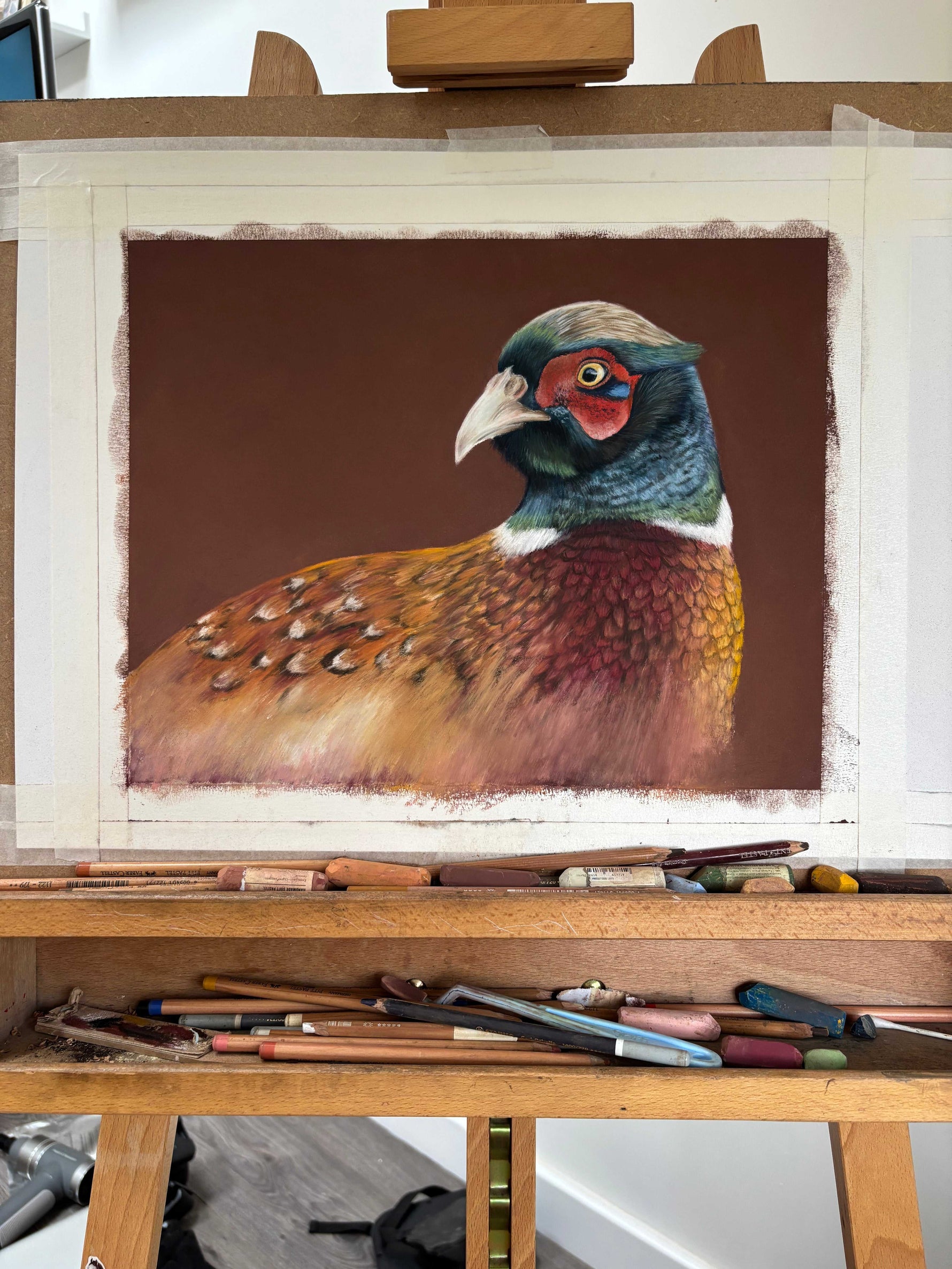 Pheasant painting 'Gerald' in progress on an easel with pastels, highlighting the creation of original country home decor wall art.