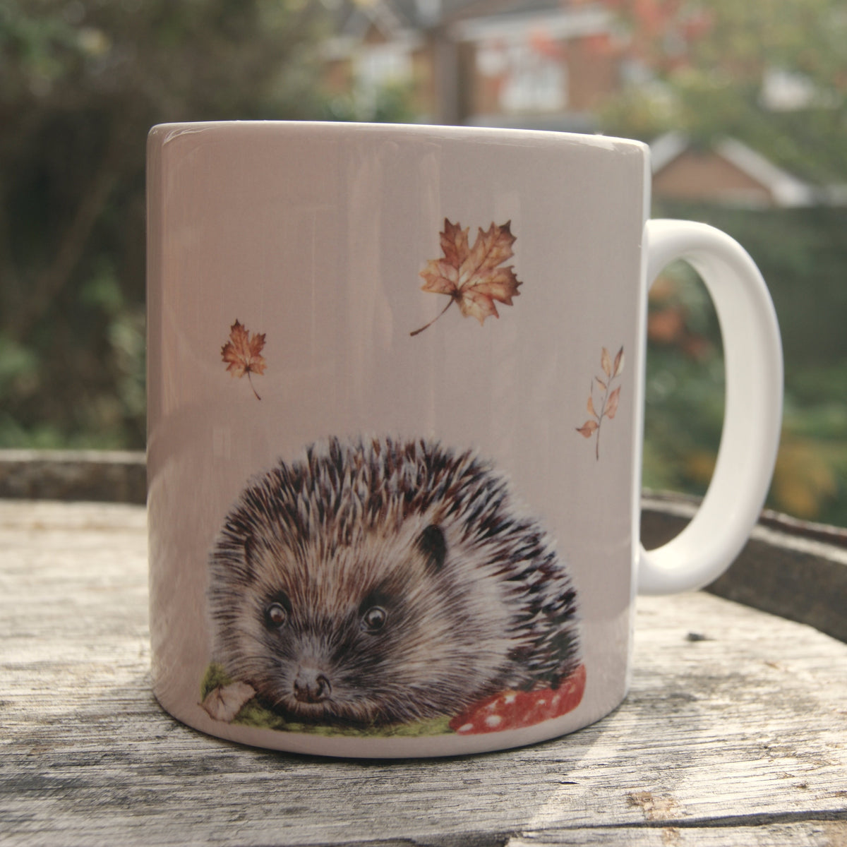 Mug with a hedgehog design on a wooden surface outdoors