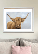 Framed Scottish Highland Cow Wall Art | Original Pastel Painting above a pastel-colored couch, enhancing cozy home decor themes.