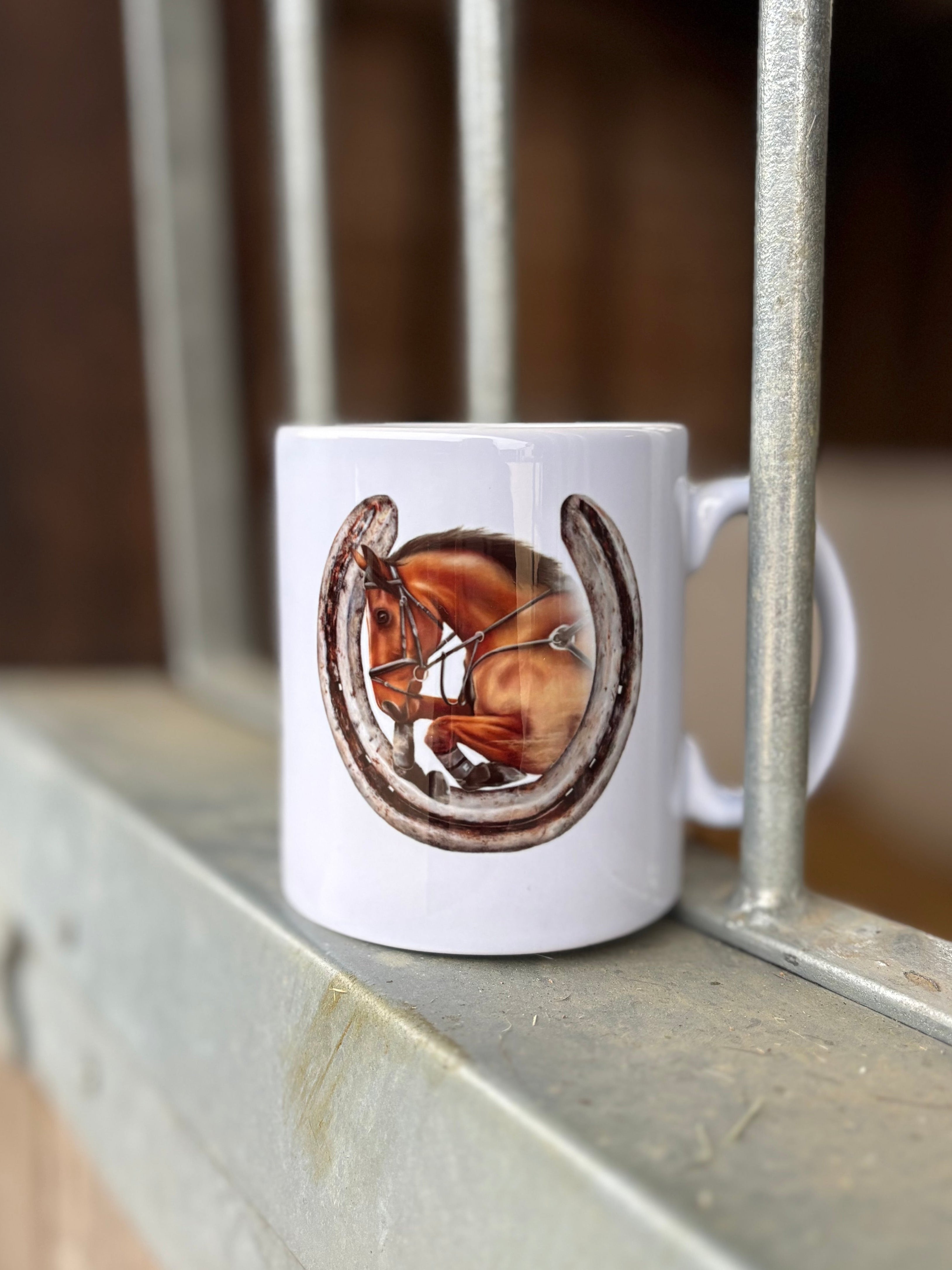 White mug with a horse and horseshoe design on a metal surface.