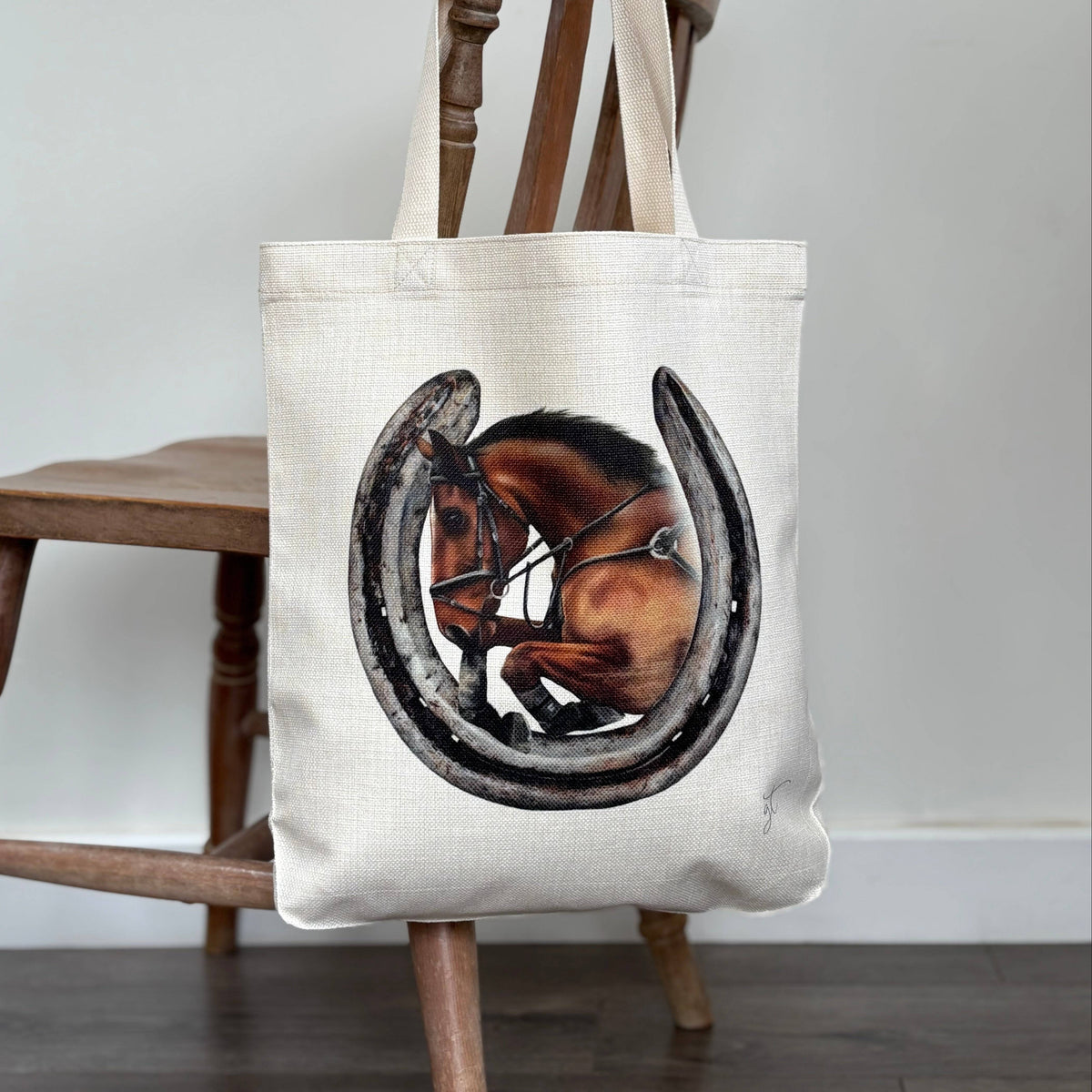 Showjumping horse and a horseshoe on a linen tote bag hung over a chair