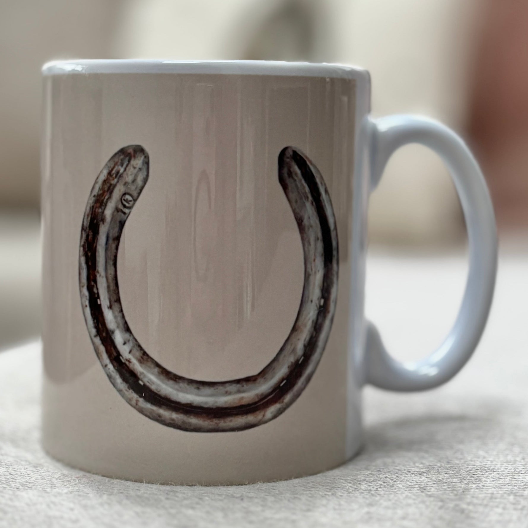 White mug with a black horseshoe design on a light surface.