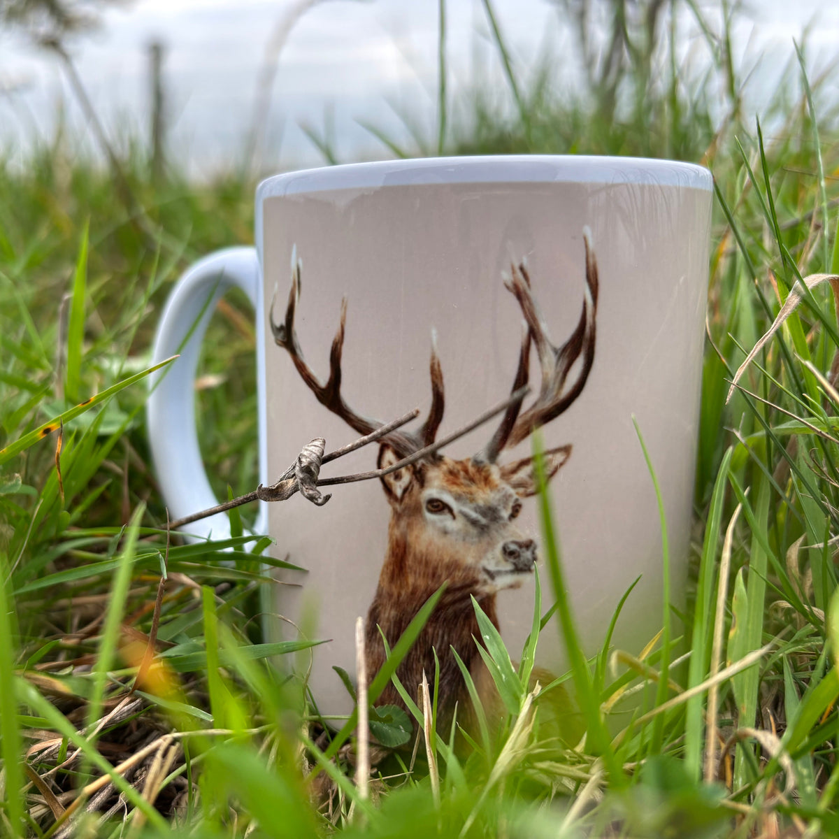 Mug with a deer design placed in grass