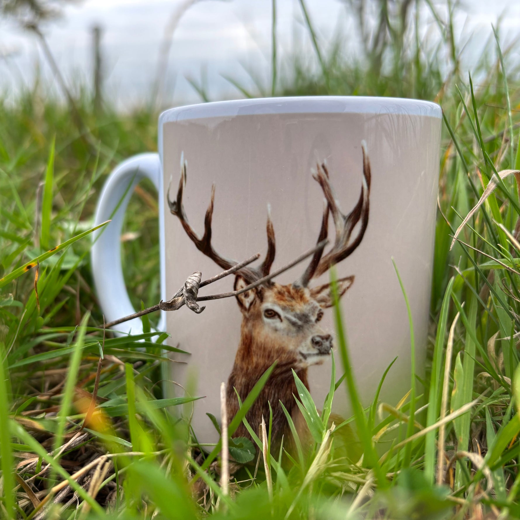 Mug with a deer design placed in grass