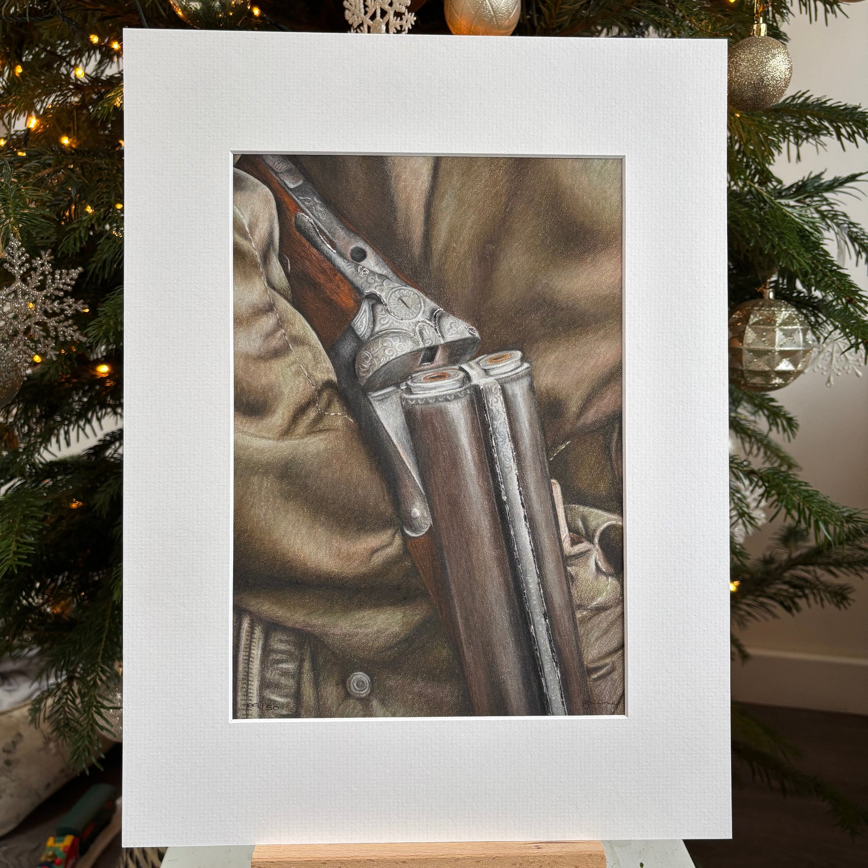 Framed picture of a rifle on a camouflage background with Christmas tree decorations.