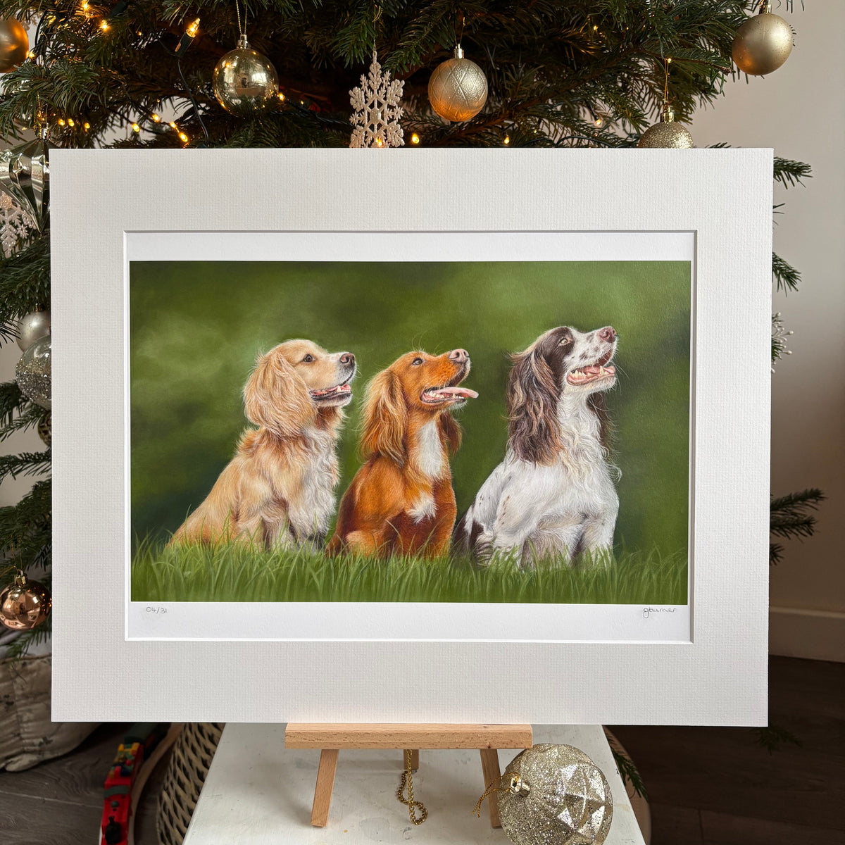 Framed artwork of three dogs lying down next to a decorated Christmas tree.