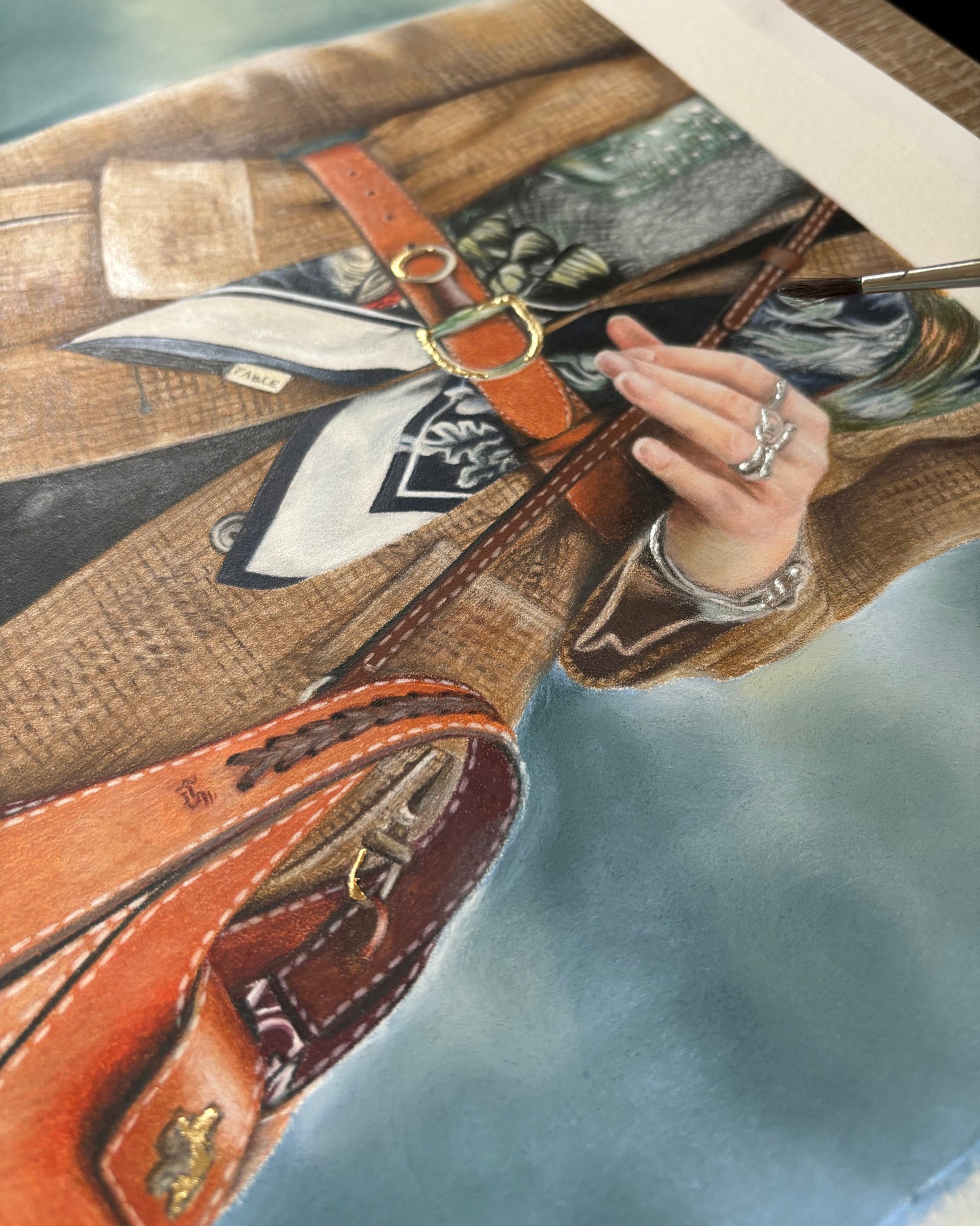 Close-up of a brown leather bag with gold accents on a blue background