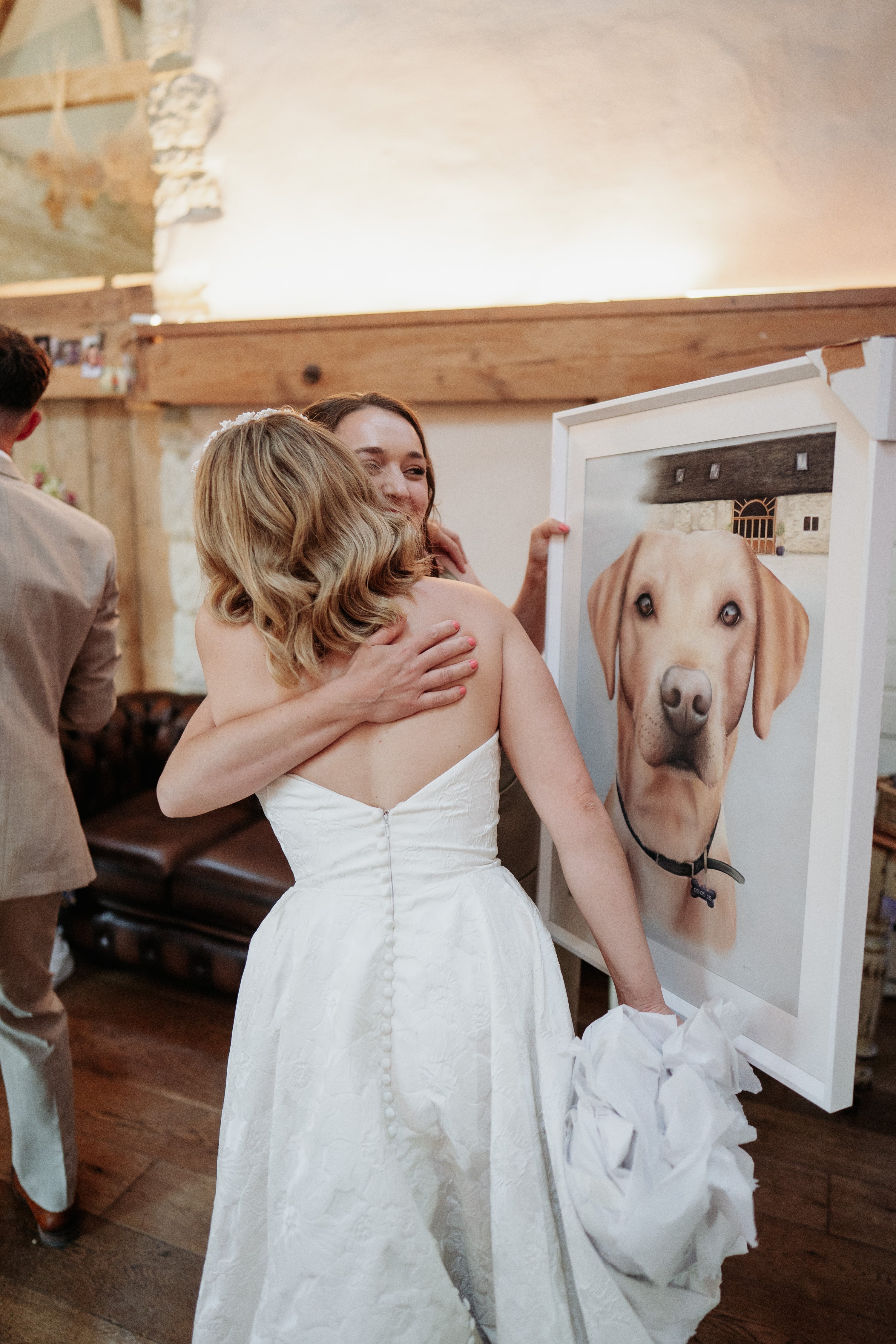 Woman in a white wedding dress holding a framed photo of a dog.